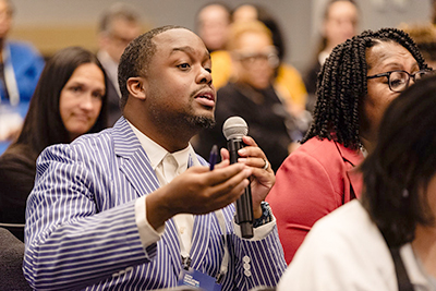 Black Man with microphone asking speaker a question.