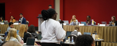 Black woman speaking into a microphone at a COSGP meeting